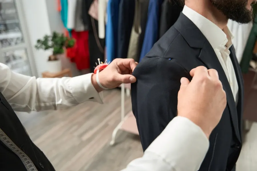 Tailor fitting a suit jacket for suit alterations in Clapham