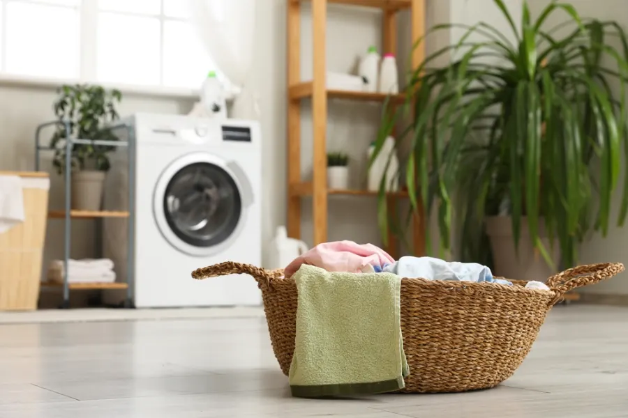 Basket of fresh laundry next to a washing machine